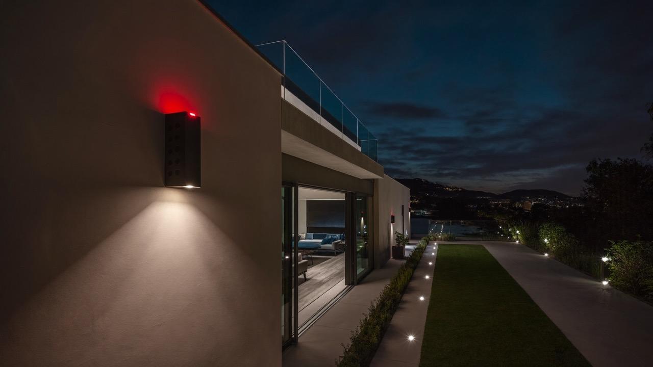 Casa protegida à noite com câmera de segurança e iluminação de perímetro